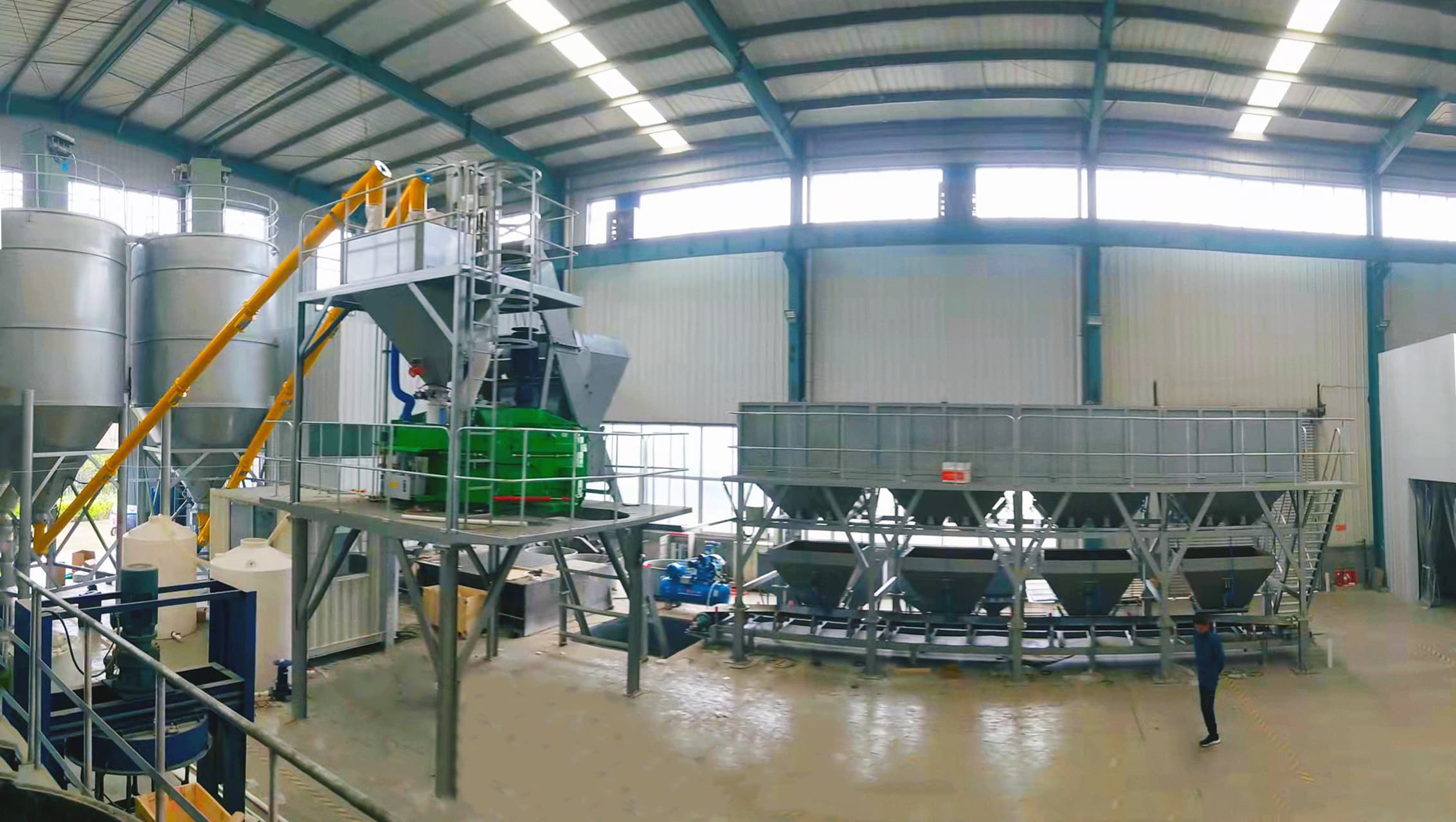 TIANYU skip-hoist plant installed inside a steel building, with silos, screw conveyor, mixer, and aggregate batcher under cover